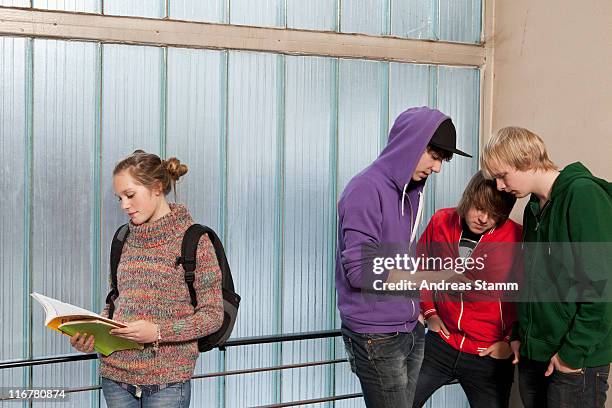 three teenage boys looking at a mobile while ignoring a teenage girl in a school stairwell - school exclusion stock pictures, royalty-free photos & images