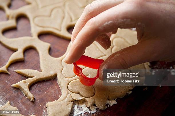 detail of a hand using a heart shape cookie cutter - pastry cutter stockfoto's en -beelden