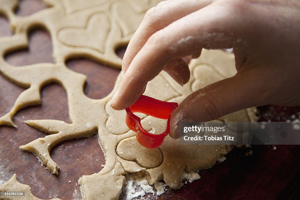 Detail of a hand using a heart shape cookie cutter