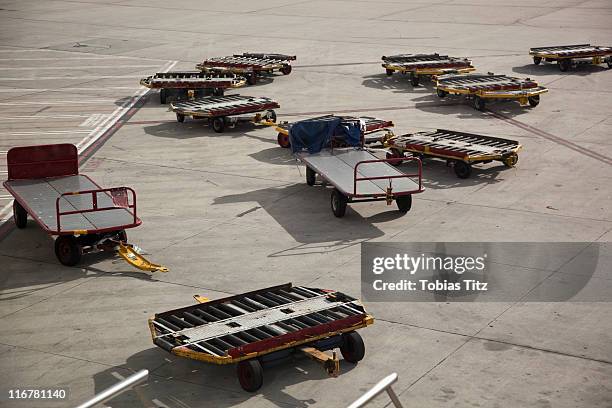 empty baggage trailers on an airport tarmac - cart stock pictures, royalty-free photos & images