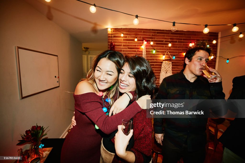 Smiling female friends hugging during holiday party in home