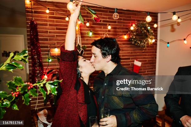 couple kissing during holiday party with friends - fun lovers unite stock pictures, royalty-free photos & images