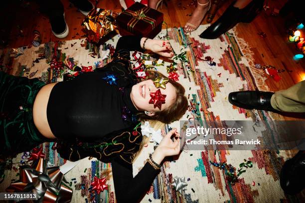 laughing woman lying on floor with bows over eyes during holiday party with friends - casual chic 個照片及圖片檔