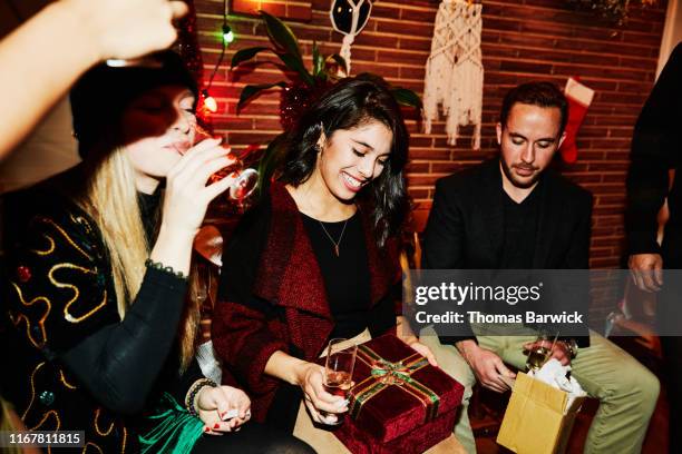smiling woman admiring present during holiday party with friends - wine gift stock pictures, royalty-free photos & images