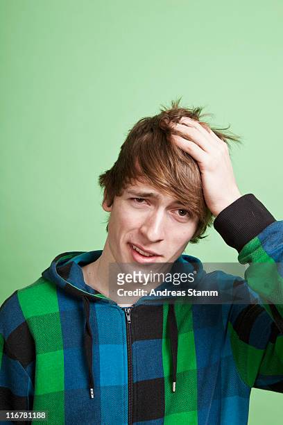 a teenage boy looking embarrassed, portrait, studio shot - peinlich stock-fotos und bilder