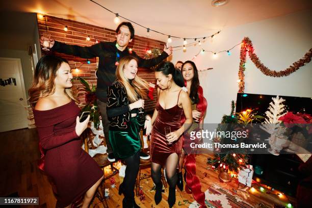 smiling and laughing friends dancing in living room during holiday party - christmas party dress stock pictures, royalty-free photos & images