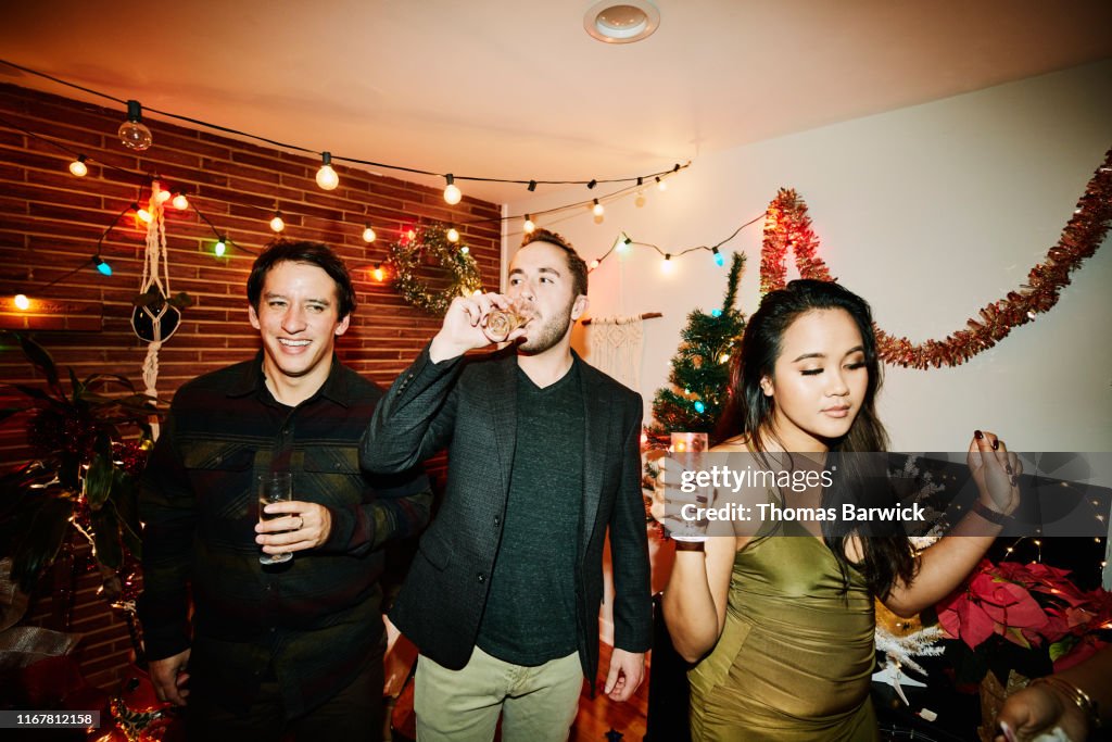 Man drinking champagne while hanging out with friends during holiday party