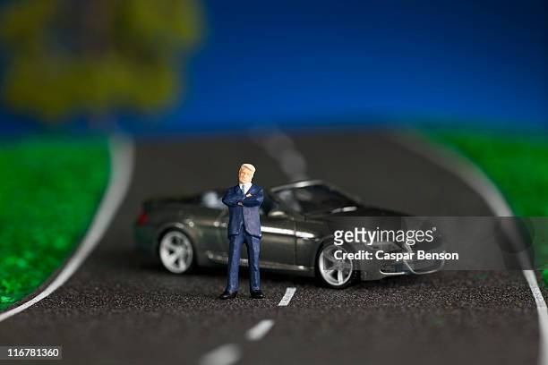 a miniature businessman figurine and miniature sports car - auto modell stock-fotos und bilder