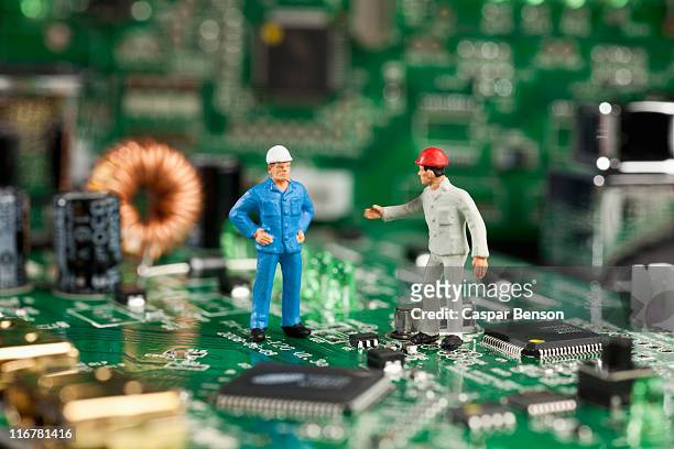 two miniature figurine men working on a computer mother board - figurine stock pictures, royalty-free photos & images