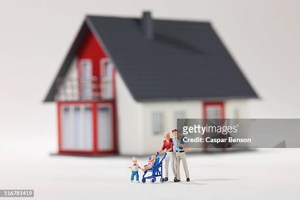 a young family of miniature figurines in front of a house - menschliche darstellung stock-fotos und bilder