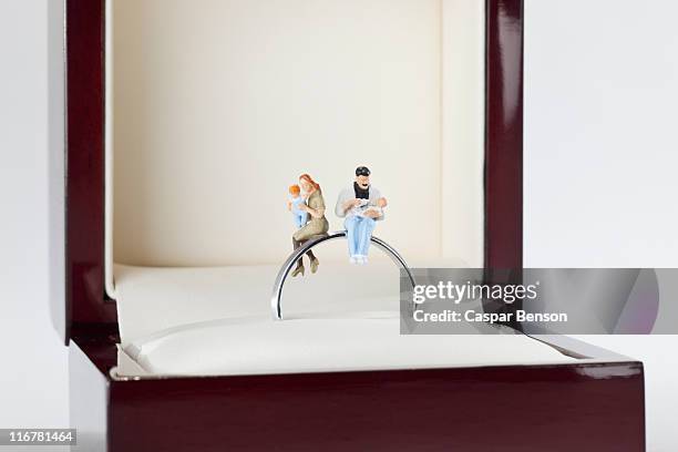 miniature figurines of a young family sitting on a wedding ring in a jewelry box - couple sitting stock pictures, royalty-free photos & images