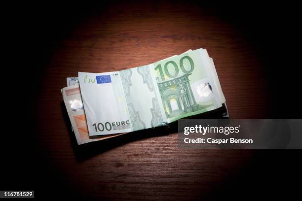 stack of money on a spot lit table - gebündelt stock-fotos und bilder