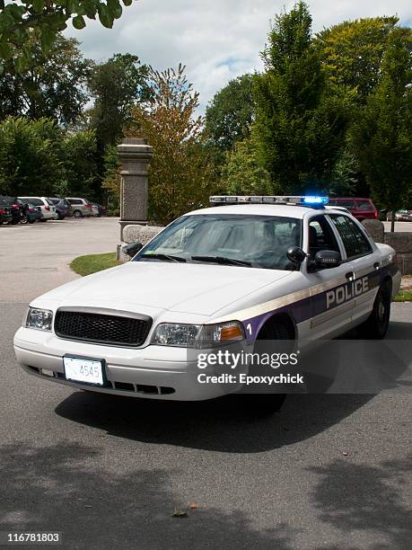 a police car with its emergency lights on parked on a street - police car stock pictures, royalty-free photos & images