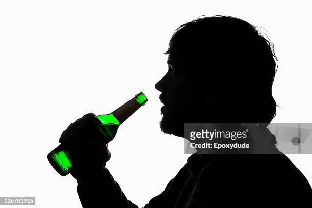 a silhouetted man about to drink from a beer bottle - beer bottle mouth stock pictures, royalty-free photos & images