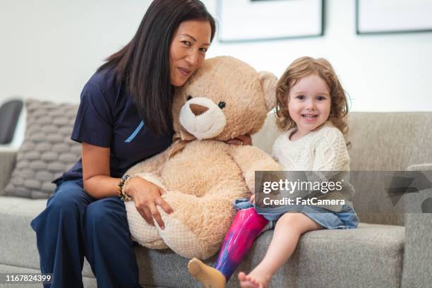 little girl with prosthetic leg poses with her doctor - amputee girl stock pictures, royalty-free photos & images