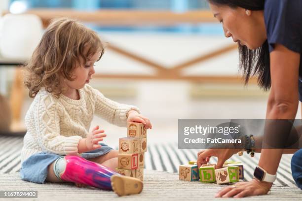 little girl with prosthetic leg at occupational therapy appointment - childhood stock pictures, royalty-free photos & images