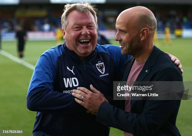 Managers Wally Downes, of AFC Wimbledon and Paul Tisdale of MK Dons share a laugh ahead of kick off in the Carabao Cup First Round match between AFC...