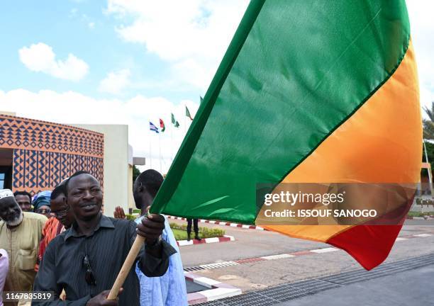 Man waves the national flag of Mali during a welcoming ceremony for the arrival of the Malian president to Ouagadougou airport on September 13, 2019...
