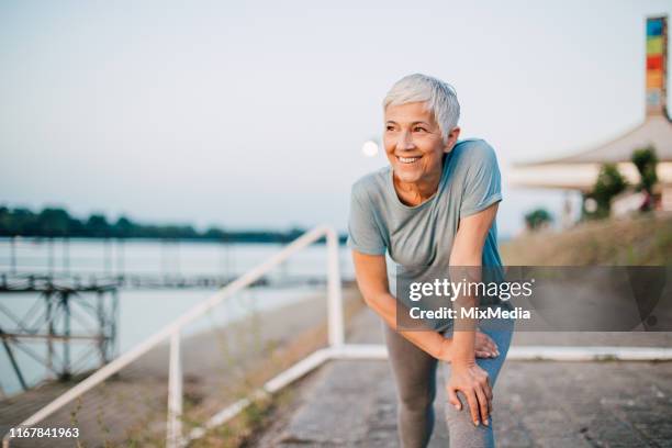 senior woman exercising by the river - flexibility stock pictures, royalty-free photos & images