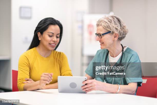 latina woman in medical consultation with mature female doctor - clinic canada diversity imagens e fotografias de stock