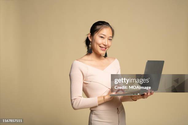 a young asian woman in casual clothing is using the laptop - laptop coloured background stock pictures, royalty-free photos & images