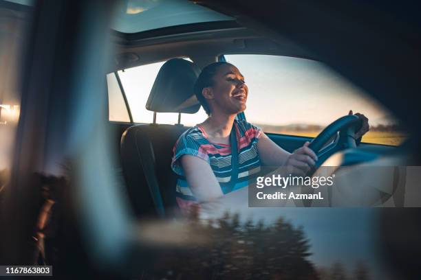 joven conduciendo coche en un día soleado - mujer conduciendo fotografías e imágenes de stock