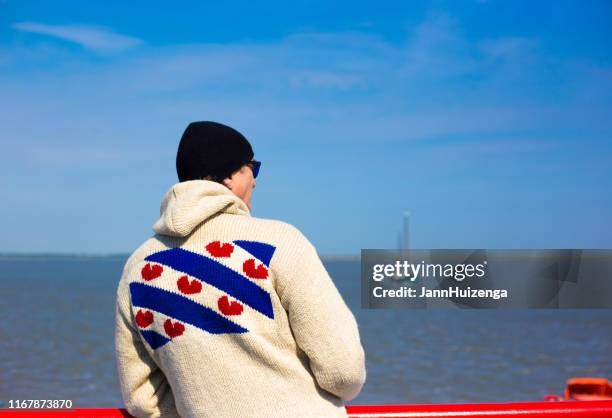 ameland island, netherlands: ferryboat passenger sporting friesian flag - friesland netherlands stock pictures, royalty-free photos & images