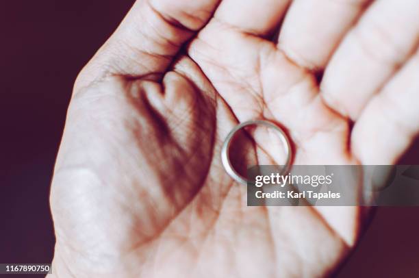 a young person is holding a wedding ring - divorce ring stock pictures, royalty-free photos & images