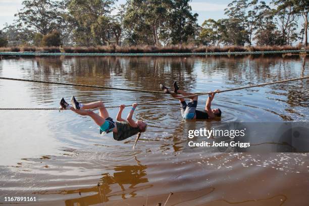 father and daughter using a rope to cross a lake during an obstacle course - hinderbana bildbanksfoton och bilder