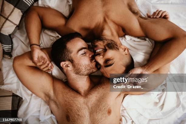 coppia gay multietnica nuda a casa che si bacia a letto - vista ad angolo alto - men kiss men in bed foto e immagini stock