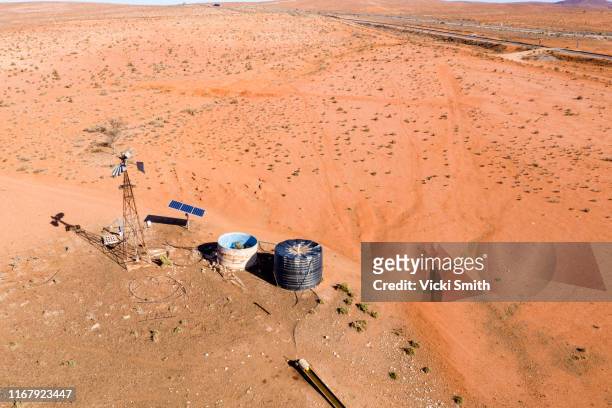 drone point of view over the red earth and windmill of the australian outback - outback windmill bildbanksfoton och bilder