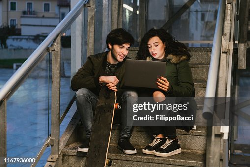 Two Friends Using A Computer Two Friends Using A Laptop Together In The City High-Res Stock Photo ...