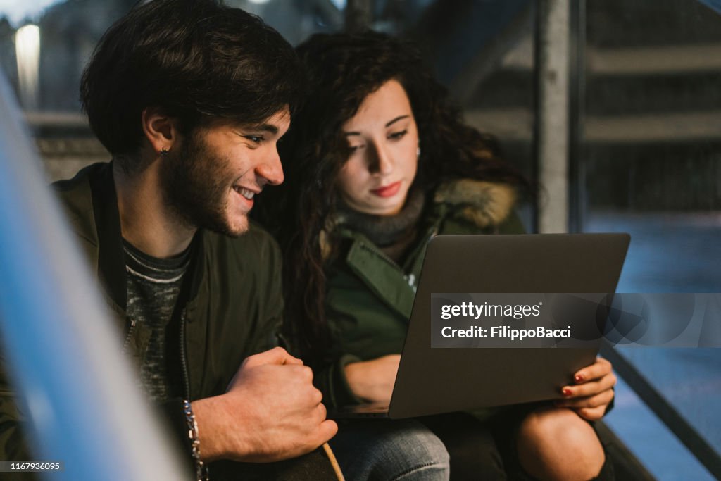 Two Friends Using A Computer Two Friends Using A Laptop Together In The City High-Res Stock Photo ...