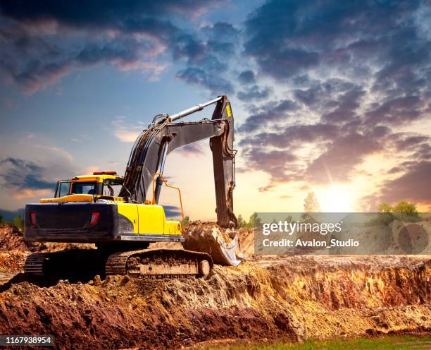 bagger auf der baustelle am abend. - caterpillar stock-fotos und bilder