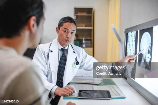 male japanese doctor going over x-ray results with patient - sala de exame médico imagens e fotografias de stock