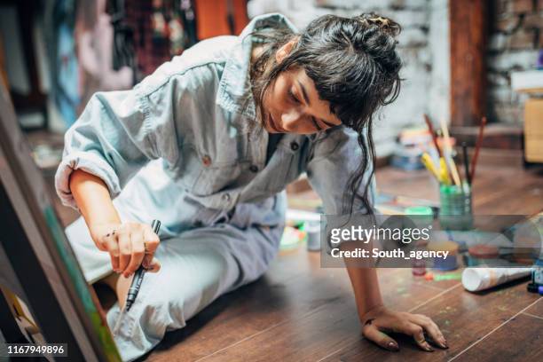 woman painting on the floor at home - artist imagens e fotografias de stock