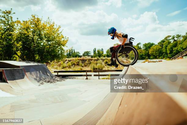 behinderte millennial frau im rollstuhl rollt die hügel in skatepark - persons with disabilities stock-fotos und bilder