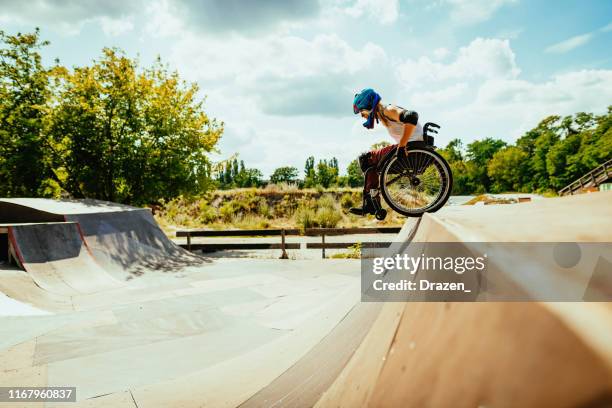 donna millenaria disabile in sedia a rotelle rotola giù per le colline nello skate park - extreme foto e immagini stock