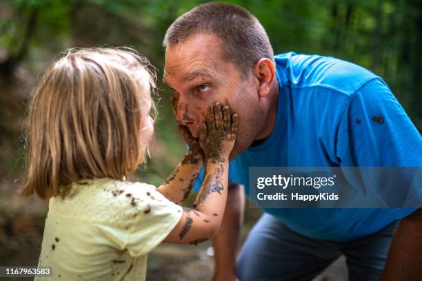 vader en dochter spelen met modder in bos - happy dirty child stockfoto's en -beelden