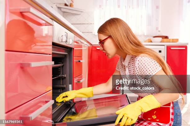 concentrated on cleaning the oven - oven stock pictures, royalty-free photos & images