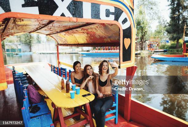 millennial women in mexico enjoying day in xochimilco gardens - mexico city tourist stock pictures, royalty-free photos & images