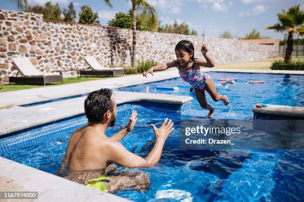 courageous little latina girl jumping in the swimming pool. - young girl jumping into swimming pool stock pictures, royalty-free photos & images
