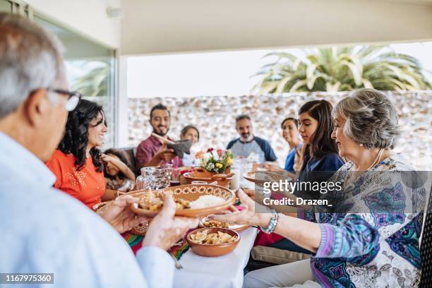latin multi generation family having feast on sunday lunch - mexico food stock pictures, royalty-free photos & images