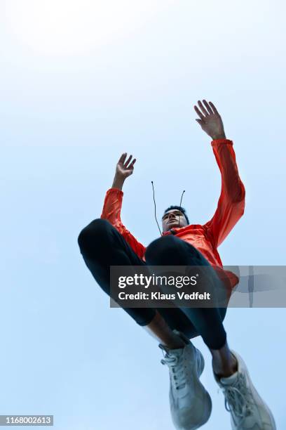 sportsman jumping against clear sky - orange jacket stock pictures, royalty-free photos & images