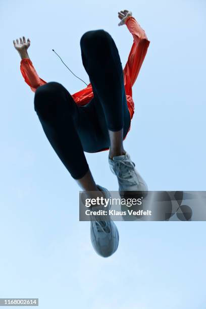 directly below shot of athlete jumping against clear sky - running shoes sky stock-fotos und bilder