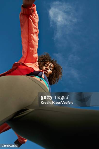 portrait of confident sportswoman exercising against blue sky - blue leggings stock pictures, royalty-free photos & images