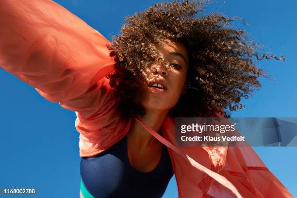 directly below shot of female athlete with curly hair against clear sky - fashion stock-fotos und bilder