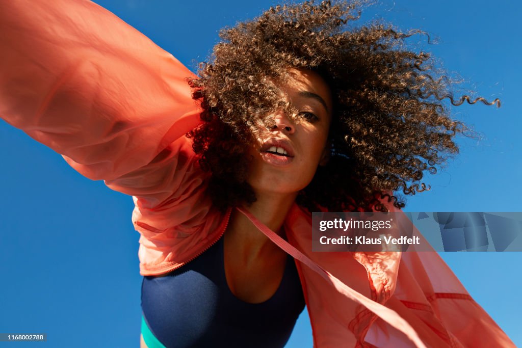 Directly below shot of female athlete with curly hair against clear sky