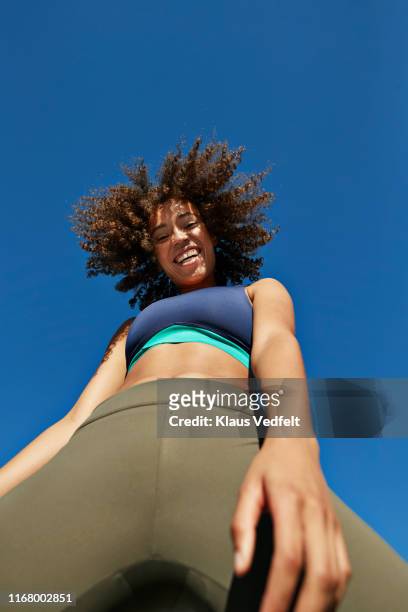 cheerful sportswoman wearing sports clothing against clear sky - young woman standing against clear sky stock pictures, royalty-free photos & images