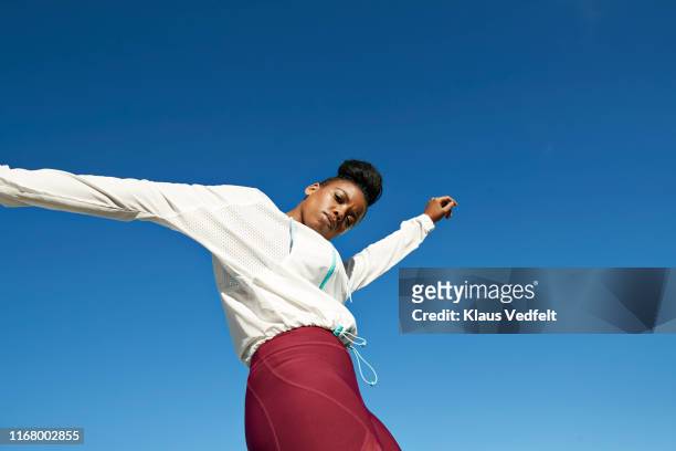 portrait of young sportswoman against clear blue sky - sicurezza di sé foto e immagini stock